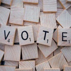 the word VOTE spelled out with wooden scrabble game tiles