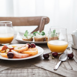breakfast food on a table containing oranges and cherries with orange juice
