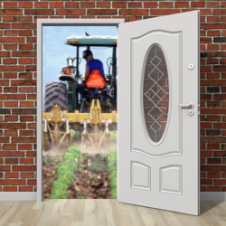 open door in a brick wall revealing a tractor on a farm crop field spraying herbicides
