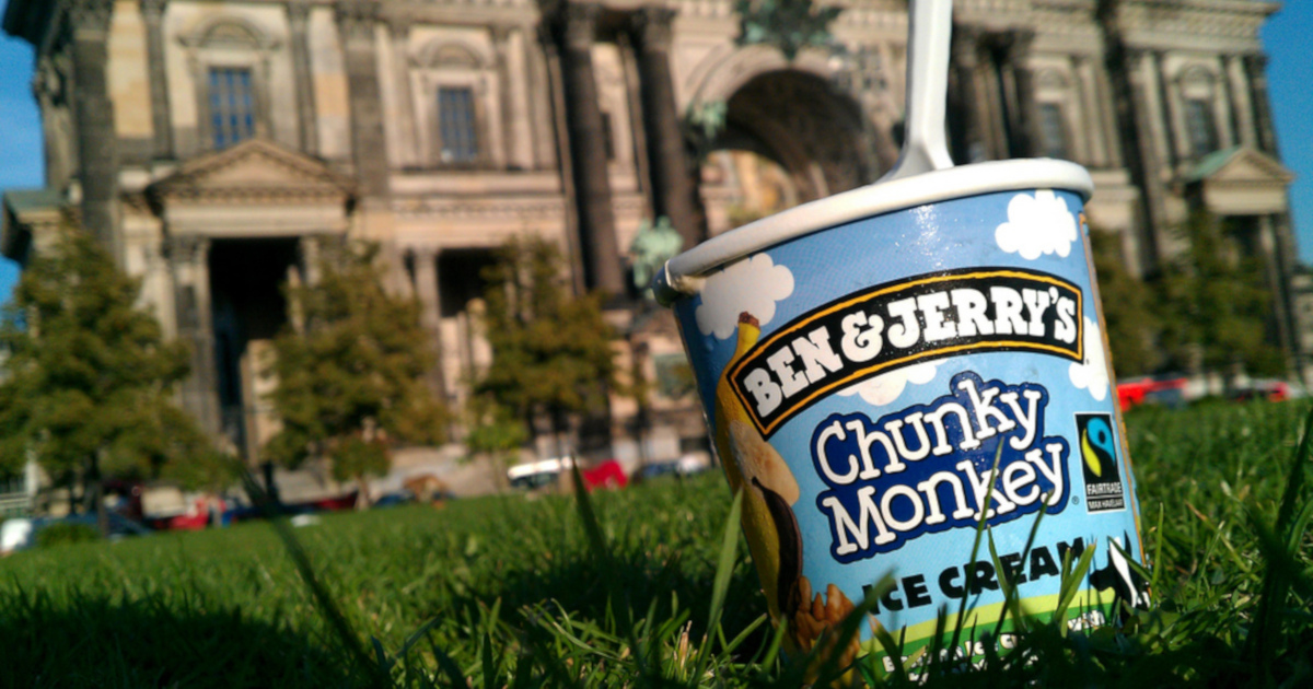 pint of Ben and Jerrys ice cream in a grassy field by a large gray building