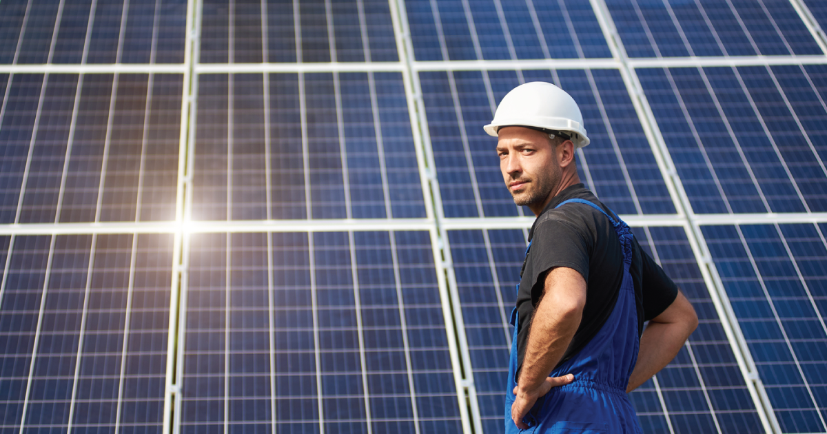 man in hard hat standing in front of a solar panel array