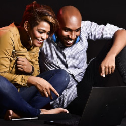 two people sitting beside each other watching a laptop computer screen