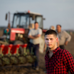 farmers standing next to a tractor in a farm field
