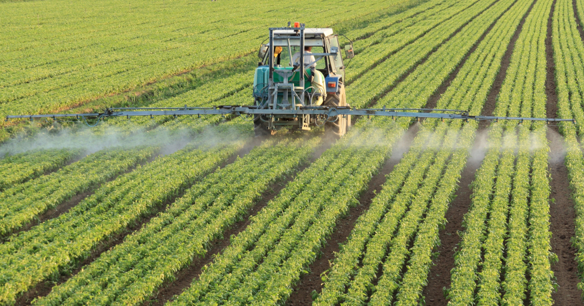 large tractor spraying crops in a farm field