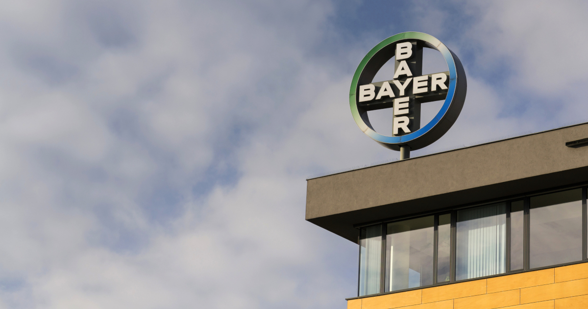 corner of a building against a cloudy sky with the BAYER logo