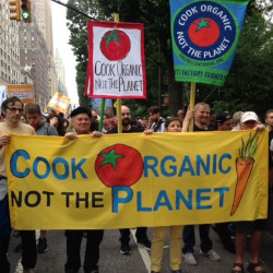 Ronnie Cummins at a protest march with several signs stating COOK ORGANIC NOT THE PLANET