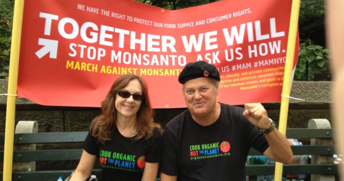 Ronnie Cummins and Katherine Paul at a protest march with signs and tshirts bearing COOK ORGANIC NOT THE PLANET