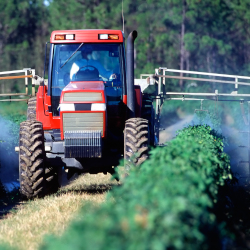 tractor on a farm field applying pesticide spray to crops