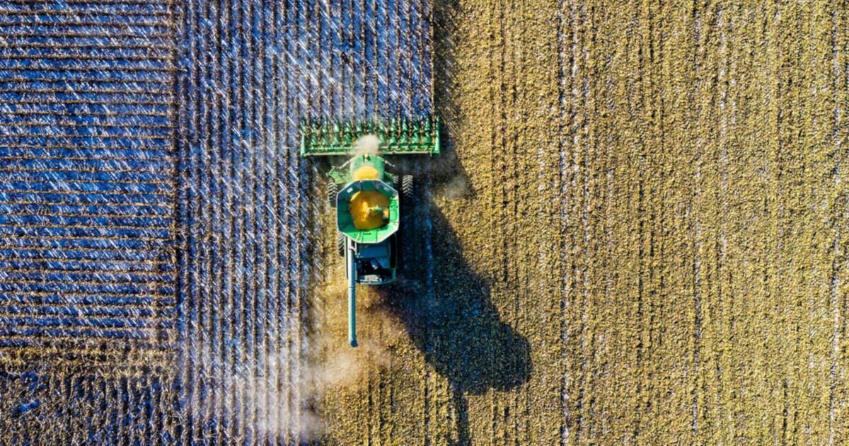 aerial view of a tractor on a farm field harvesting a crop