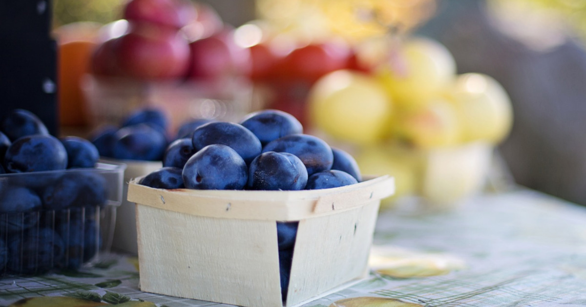 fresh fruit and produce like plums in small wooden containers for a farmers market sale