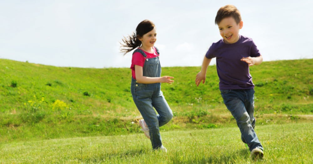 two children running through a grassy field