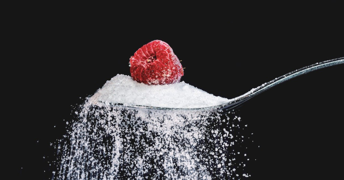 granulated sugar falling off a spoon with a raspberry on top