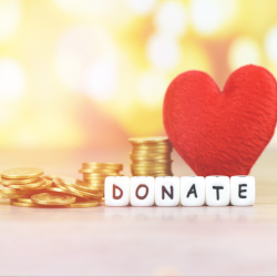 stacks of gold coins beside a red felt fabric heart and white and black blocks that spell DONATE