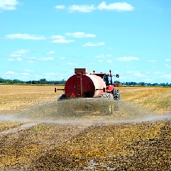 tractor on a farm spraying liquid chemical fertilizer on a crop field