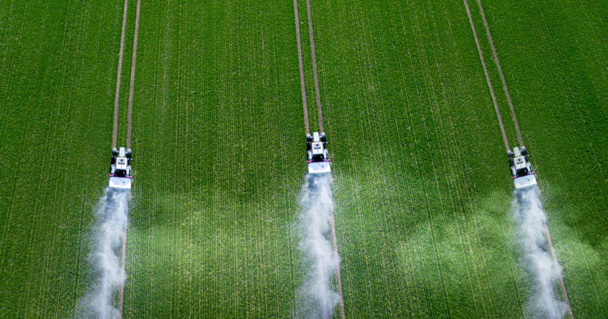 three tractors on a farm field spraying crops down with pesticides