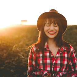 woman farmer in a crop field at sunset smiling