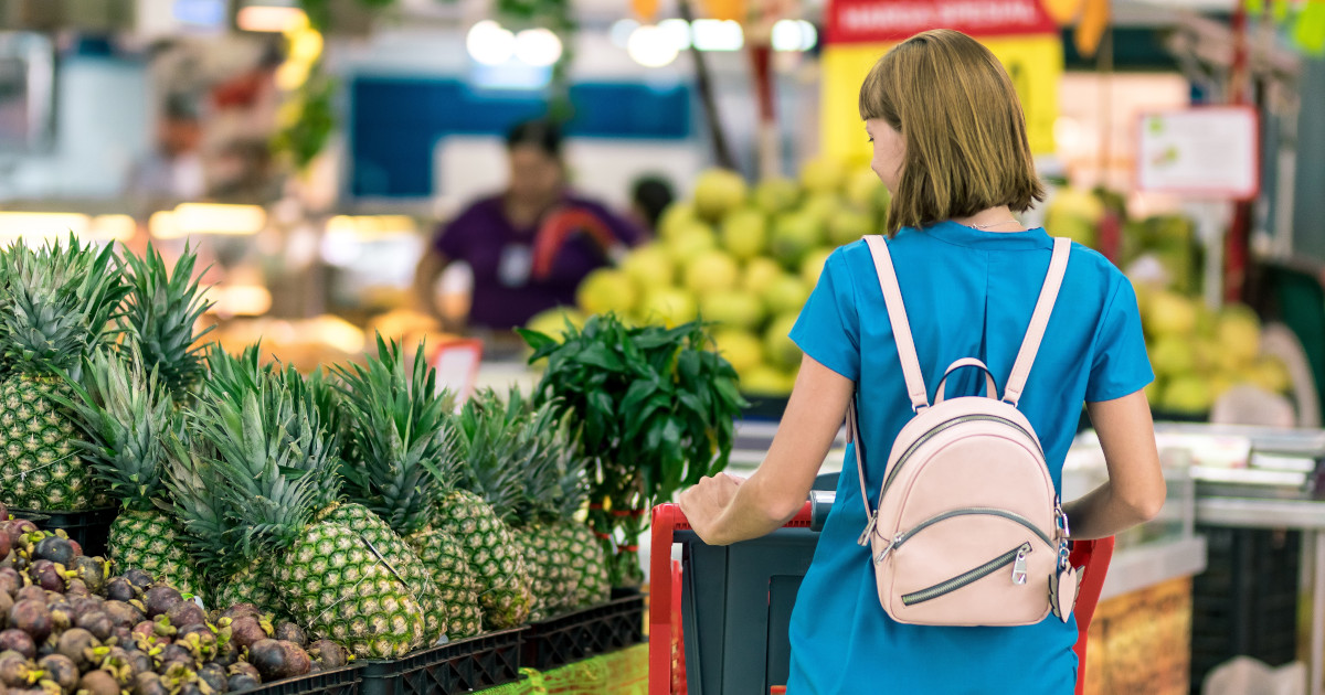 woman shopping in a grocery store in the produce section by a pineapple display