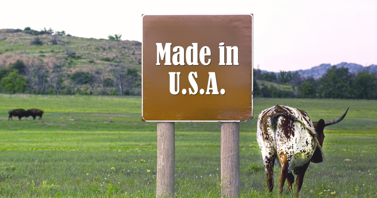 cattle grazing in a mountain landscape near a brown sign that says MADE IN USA