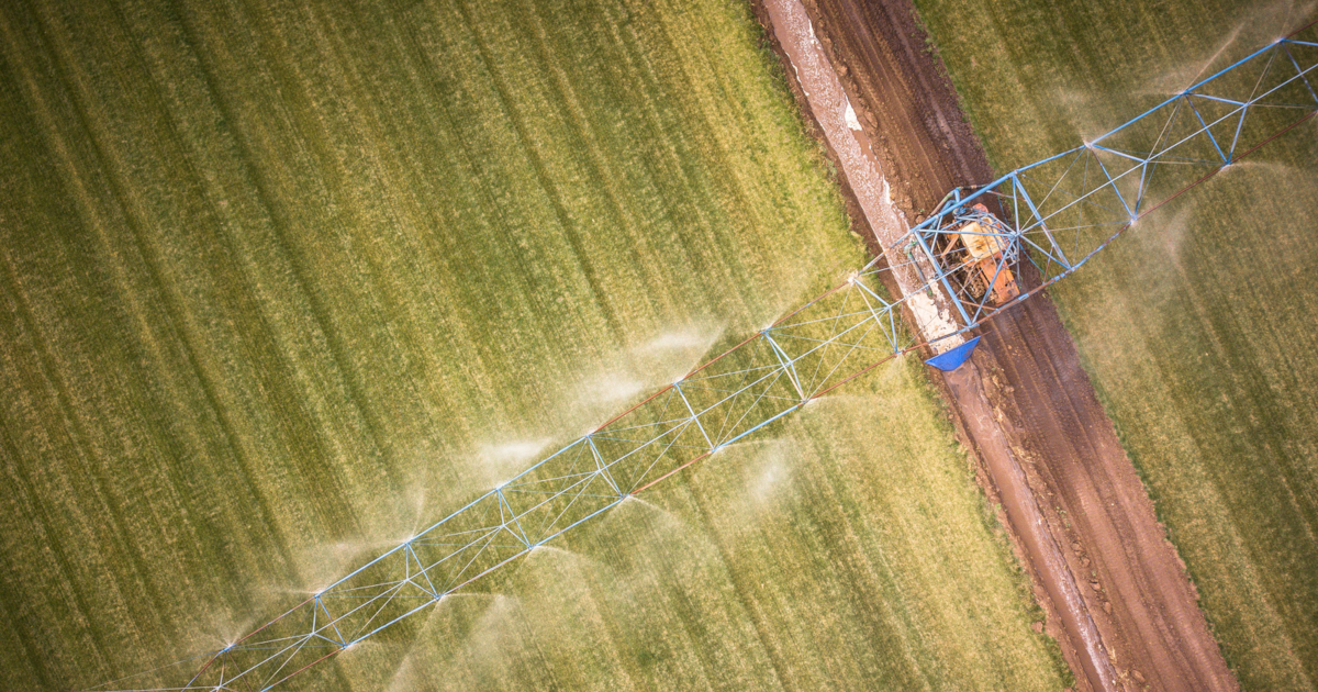 overhead aerial view of farm machinery on a crop field spraying herbicides