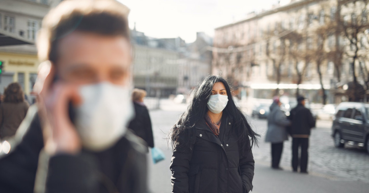 two people in a city street wearing face masks