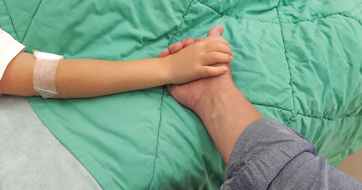Sick child holding parents hand.