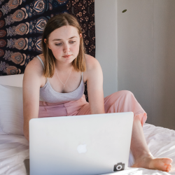 woman sitting on a bed reading from a laptop computer