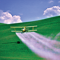 air plane spraying a crop field on a farm