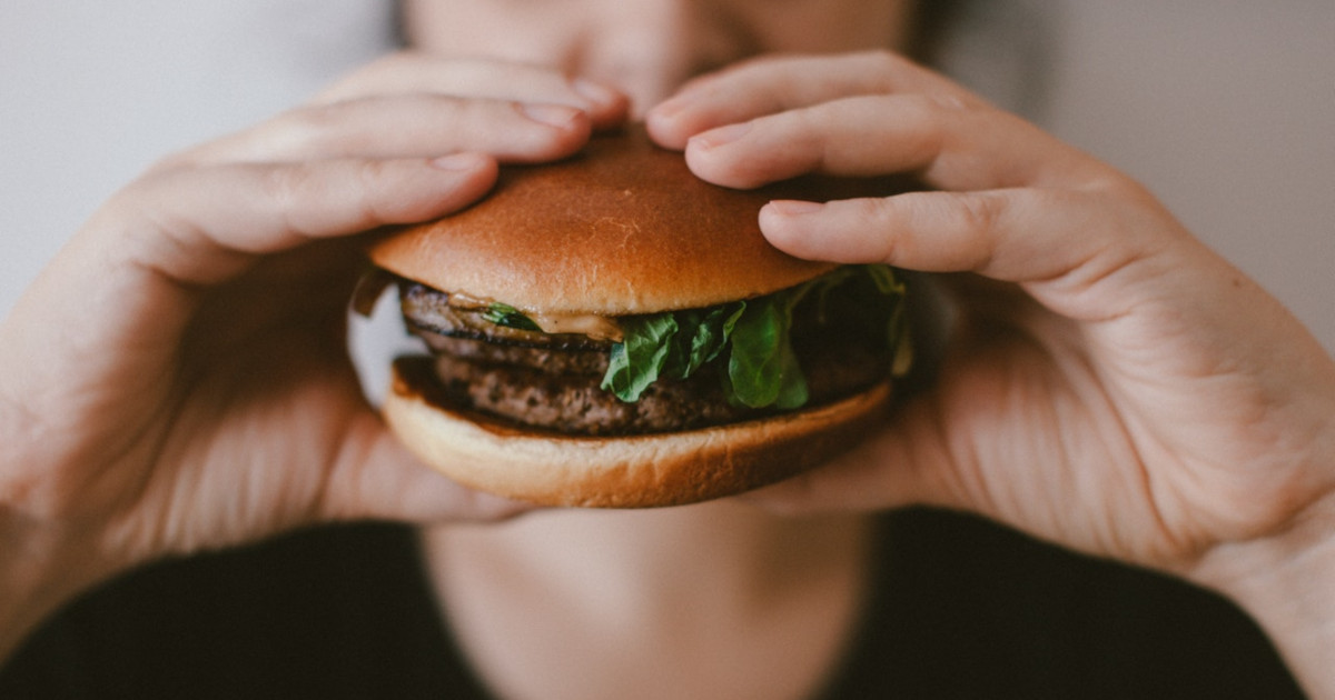 man in a black shirt holding a hamburger