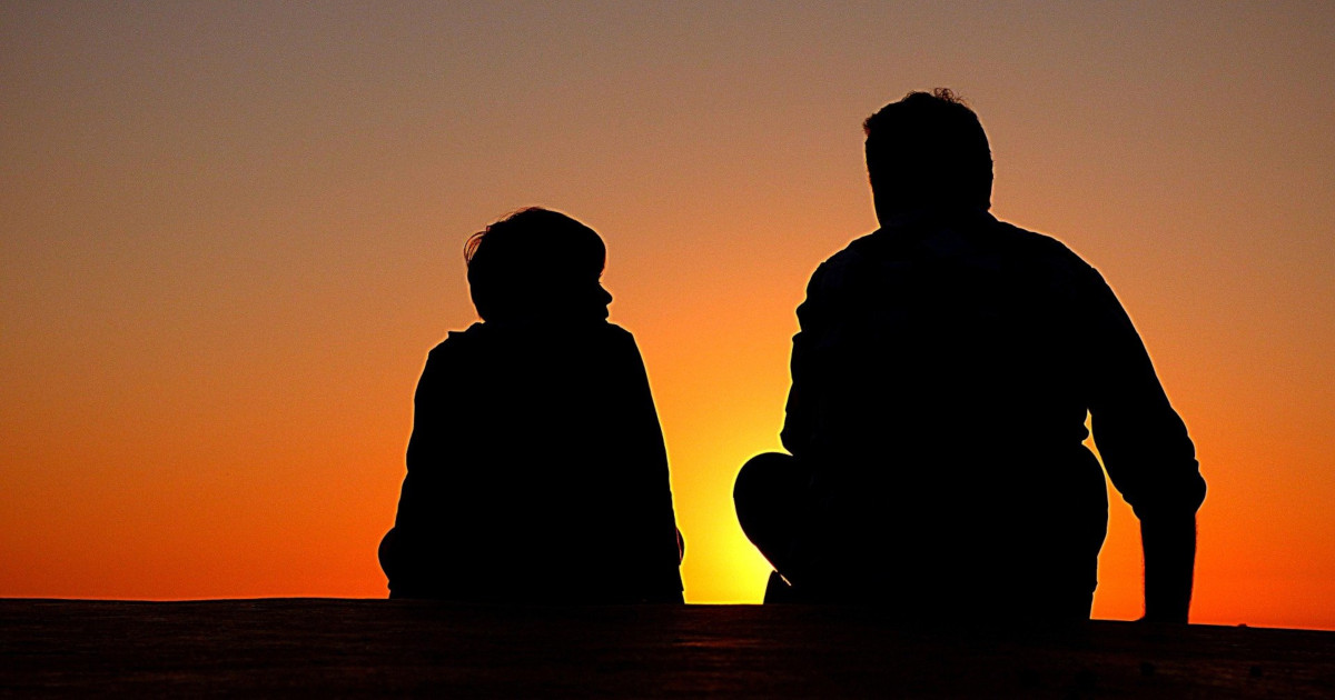 two silhouettes sitting in the sunset