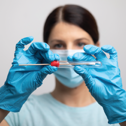 doctor with blue gloved hands holding a testing swab