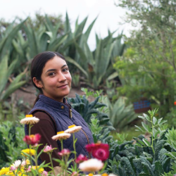 woman standing in a garden field with flowers and agave